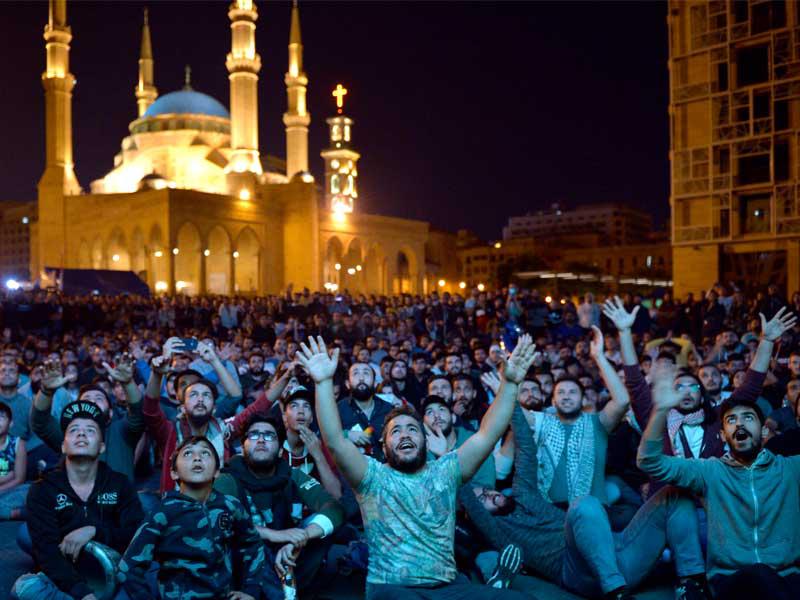  متظاهرون في ساحة الشهداء مساء أمس الأول يتابعون مباراة لكرة القدم بين المنتخب اللبناني وكوريا الشماليةt (اي بي ايه)