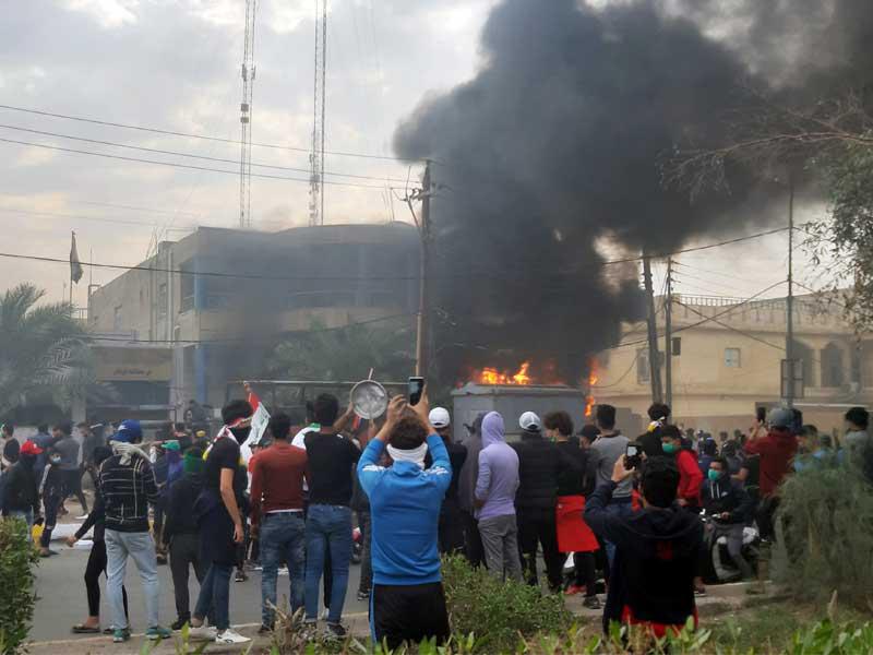 محتجون بمحيط مقر الوقف الشيعي عقب إضرام النار فيه بالناصرية أمس (رويترز)