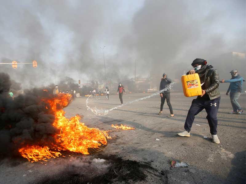 محتجون يحرقون إطارات لإغلاق طريق رئيسي في البصرة أمس (رويترز)