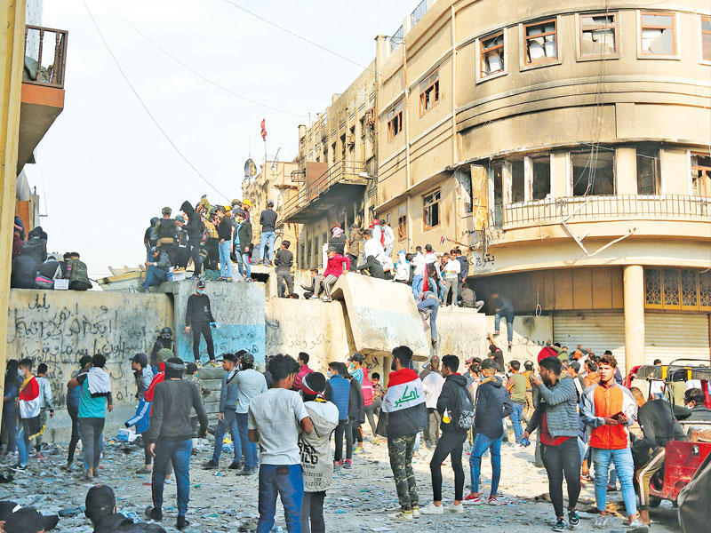 متظاهرون عند فاصل أسمنتي وضعته قوات الأمن بشارع الرشيد قرب المنطقة الخضراء وسط بغداد أمس (أ ف ب)