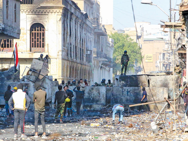 محتجون قرب حاجز أسمنتي بشارع الرشيد وسط بغداد أمس (أ ف ب)