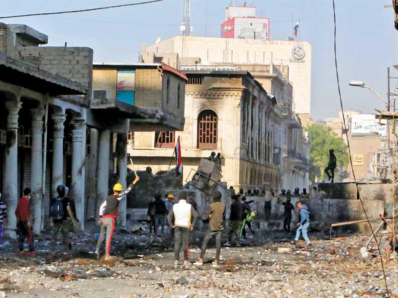 محتجون قرب حاجز أسمنتي في شارع الرشيد وسط بغداد أمس (أ ف ب)n