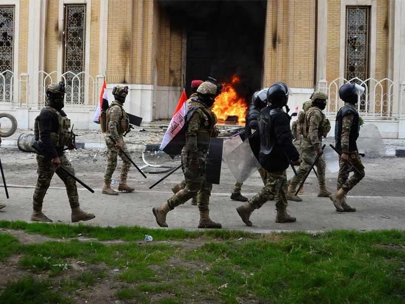 قوات أمن بمحيط مرقد محمد باقر الحكيم بعد إضرام النار بأحد بواباته من قبل مجهولين خلال احتجاجات في النجف أمس (أ ف ب)