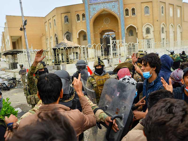 محتجون عراقيون وحراس مرقد محمد باقر الحكيم في النجف أمس t(أ ف ب)