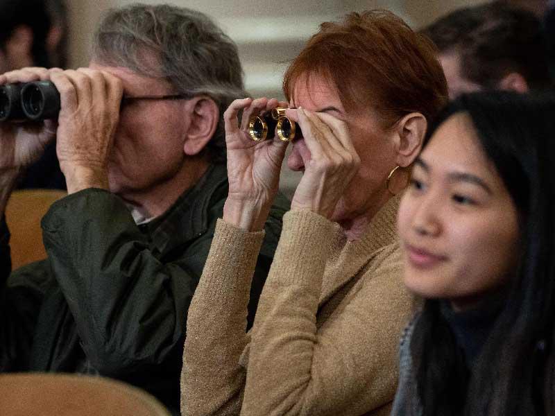 أميركيان يستخدمان منظارين لمتابعة جلسة الاستماع في الكابيتول هيل مقر الكونغرس بواشنطن أمس الأول      (أ ف ب) 