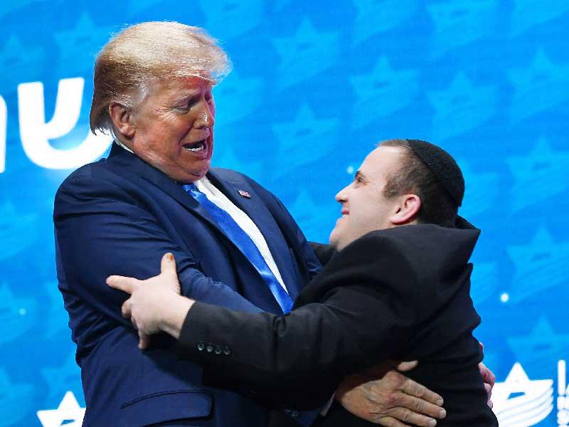 ترامب معانقاً أحد أفراد فرقة «شالفا» الموسيقية خلال التجمّع في فلوريدا أمس الأول (أ ف ب)