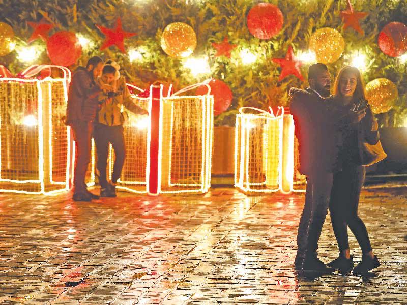 لبنانيون يلتقطون «سيلفي» أمام زينة عيد الميلاد في جبيل (أ ف ب)