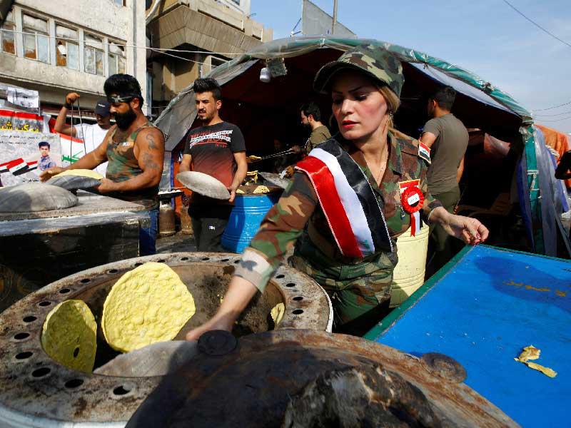 عراقيون يساعدون في إعداد الطعام لمحتجي التحرير وسط بغداد (رويترز)