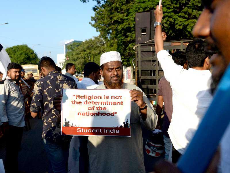 المتظاهرون يحملون لافتات ويطلقون شعارًا أثناء احتجاج على مشروع قانون تعديل المواطنة