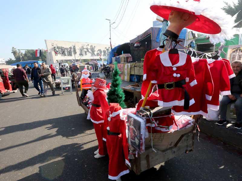 بائع يعرض ملابس خاصة باحتفالات «عيد الميلاد» لدى المسيحيين وسط ساحة التحرير في بغداد            (أ ف ب)