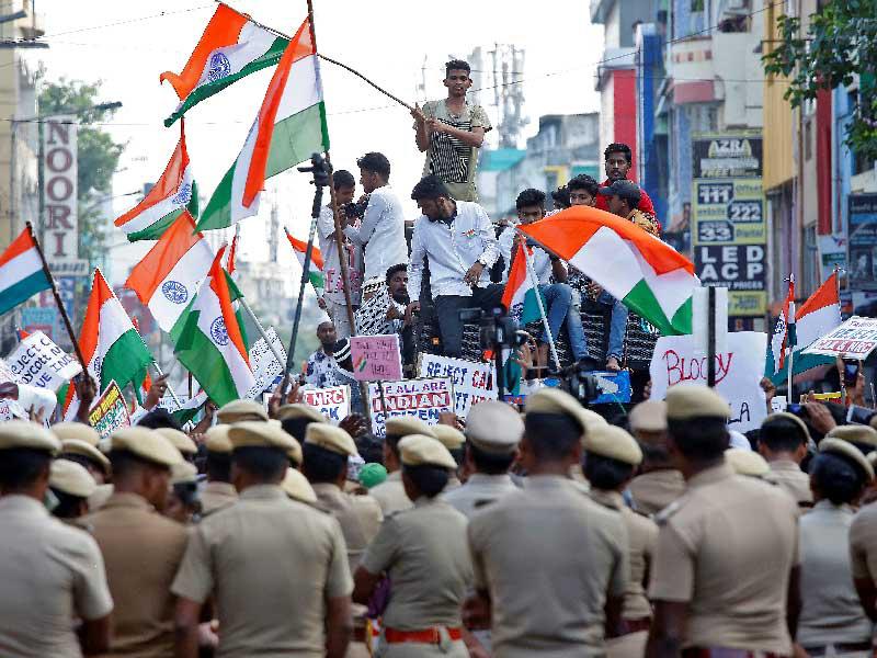 يقف ضباط الشرطة في حذر أثناء حضور المتظاهرين مسيرة احتجاج ضد قانون الجنسية الجديد