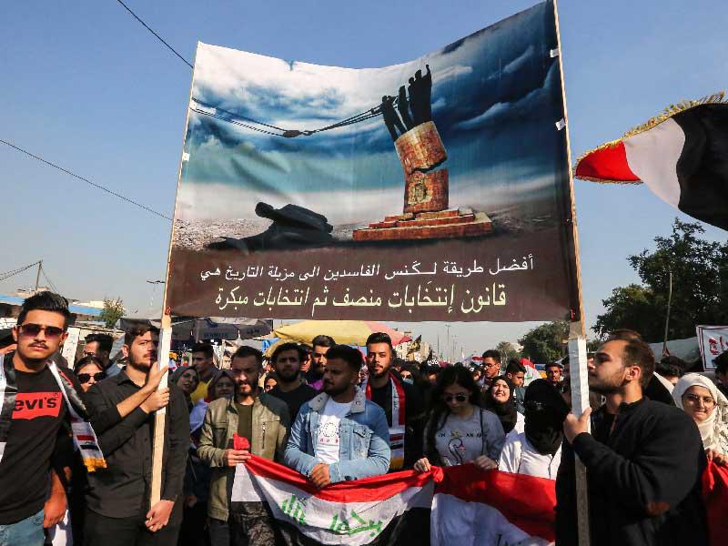 متظاهرون يرفعون لافتة تظهر اقتلاع الفاسدين كما اقتلع تمثال صدام في بغداد أمس  (أ  ف ب)