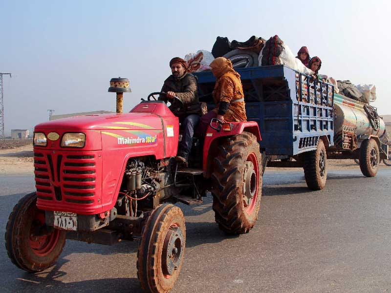 أسرة سورية تفر من معرة النعمان على جرار زراعي أمس (أ ف ب)