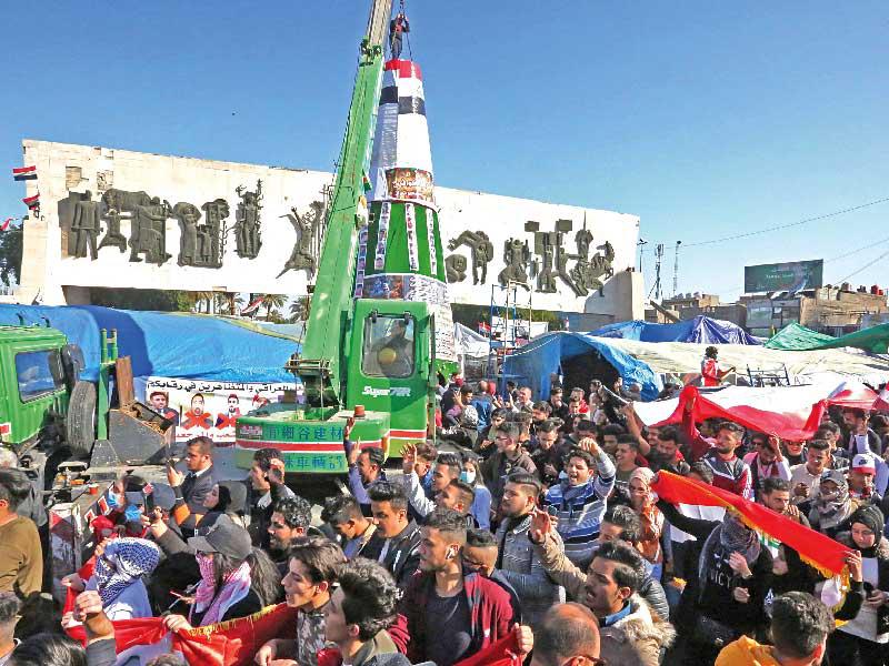 محتجون يرفعون شجرة «عيد الميلاد» قرب ساحة التحرير بوسط بغداد أمس (أ ف ب)