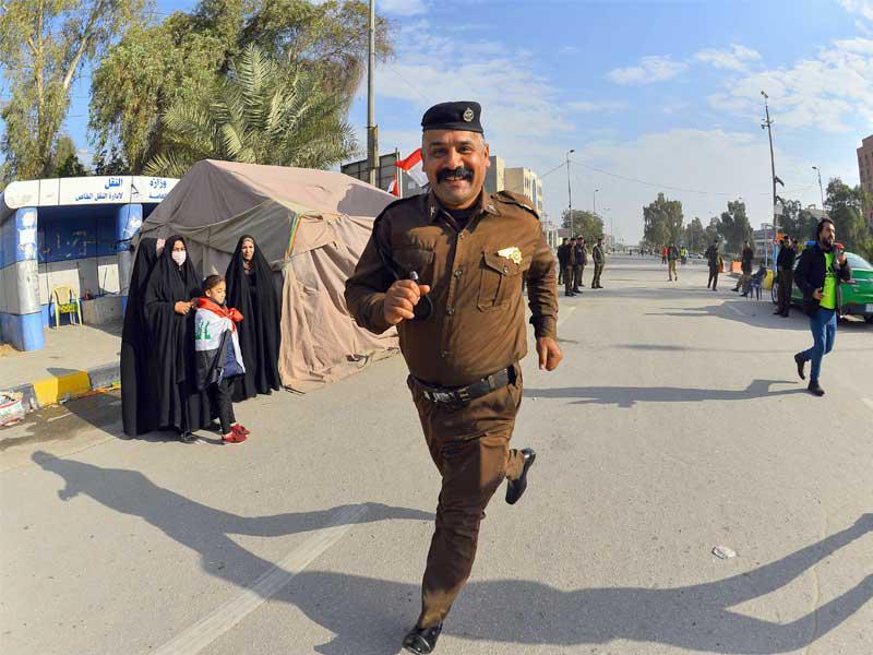 شرطي عراقي يشارك في ماراثون بجامعة الكوفة في النجف  (أ ف ب)