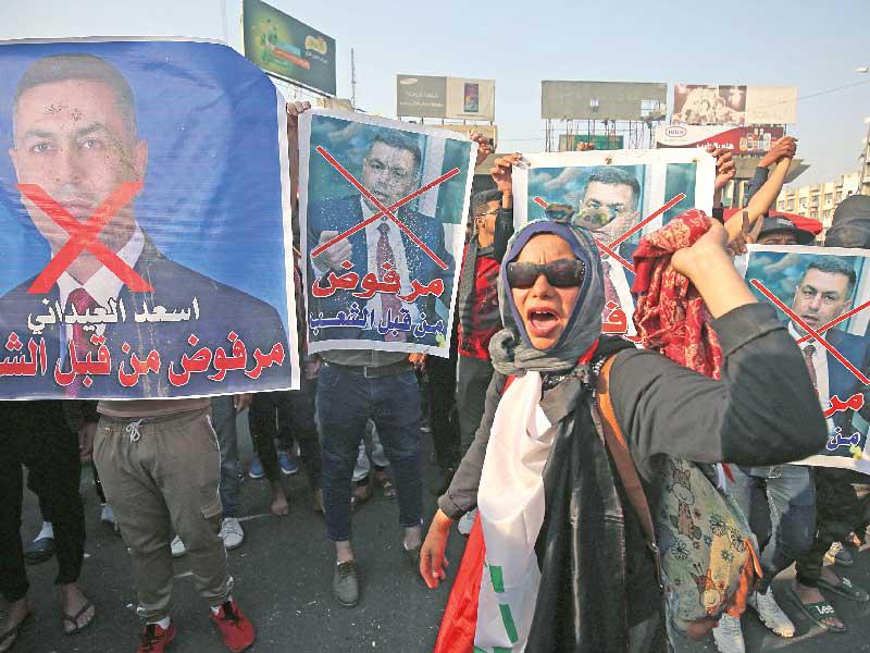 متظاهرون يحملون صورا ترفض تكليف العيداني في بغداد أمس (أ ف ب)