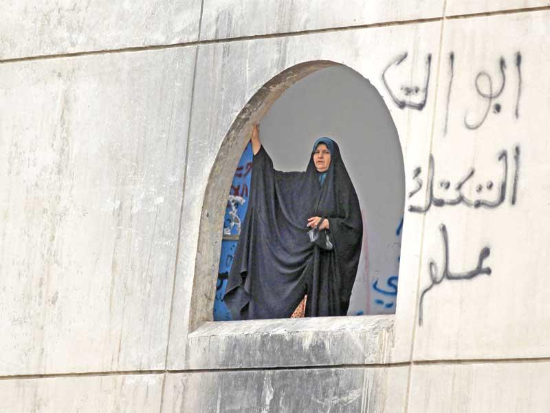 عراقية تطل من إحدى نوافذ «المطعم التركي» معقل الاحتجاجات في «ساحة التحرير» وسط مدينة بغداد العراقيى (أ ف ب)