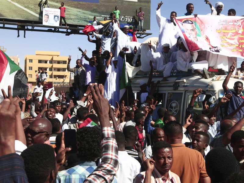 سودانيون يرفعون صور الخير في أم درمان بعد صدور القرار بإعدام 27 من جهاز الاستخبارات السابق (أ ف ب)