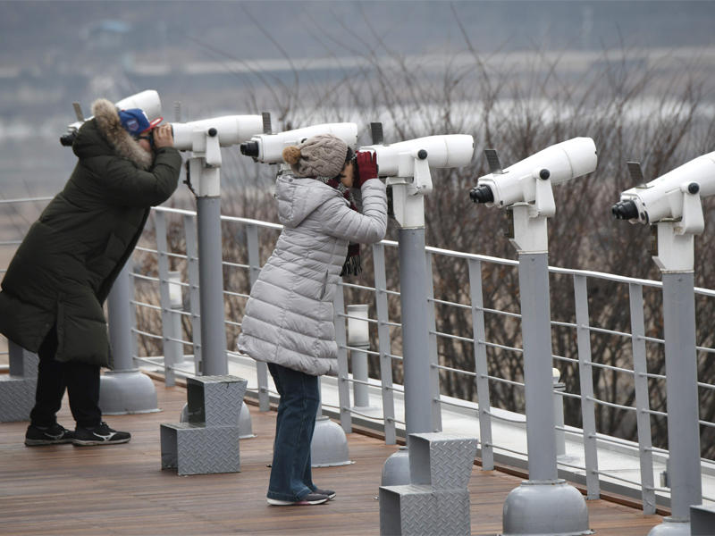 سائحتان في المنطقة المنزوعة السلاح بين الكوريتين تراقبان من خلال منظارين الجزء الشمالي أمس (أ ف ب)