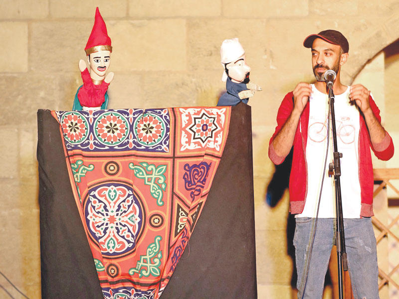 مصريون يشاهدون مسرحية دمى في حي الجمالية بالقاهرة أمس (أ ف ب)