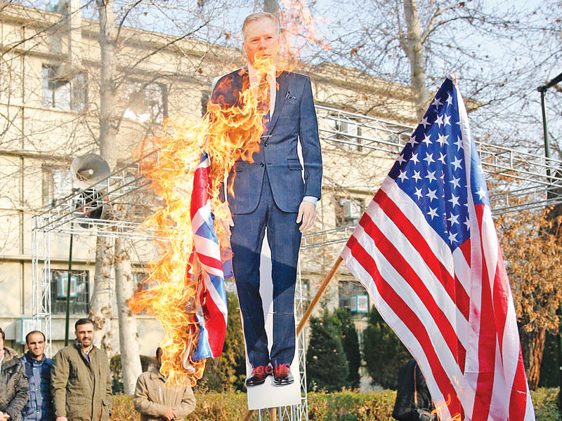 متشددون يحرقون مجسماً للسفير البريطاني والعلم الأميركي بطهران أمس (أي بي أيه)n