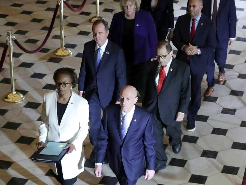 موظّفون في مجلس النواب ينقلون القرار الاتهامي لتسليمه إلى مجلس الشيوخ أمس الأول (رويترز)