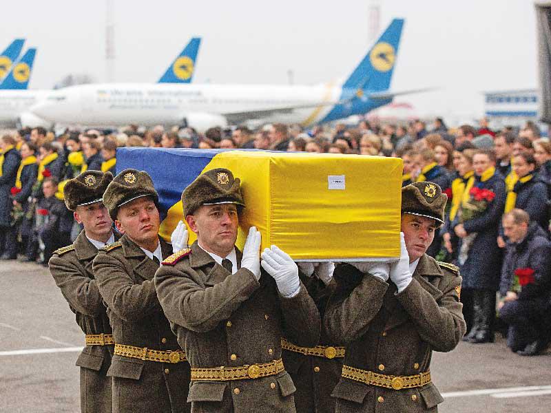 جنود أوكرانيون يحملون رفات أحد ضحايا «الأوكرانية» في كييف أمس (إي بي أيه)