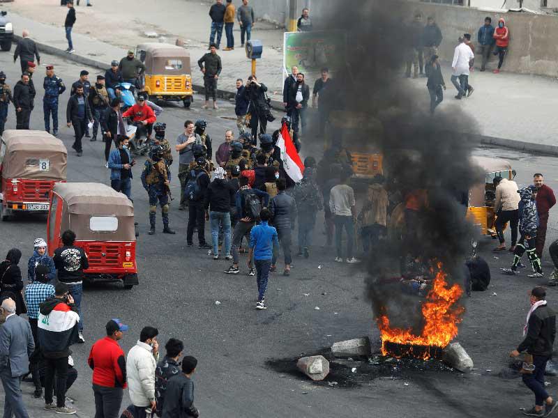 متظاهرون عراقيون يقطعون أحد الطرق في بغداد أمس (رويترز)