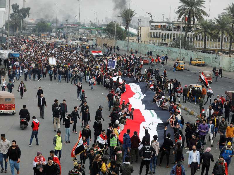 طلاب جامعيون يحملون راية عراقية ضخمة خلال الاحتجاجات المستمرة المناهضة للحكومة في العاصمة العراقية بغداد