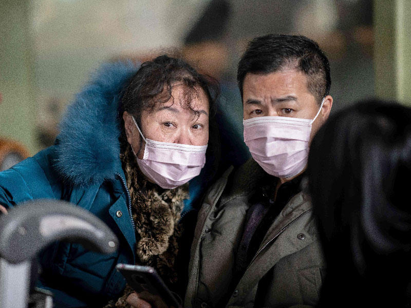 يرتدي الأشخاص الذين المسافرون أقنعة واقية أثناء توجههم إلى منطقة المغادرة في مطار العاصمة بكين