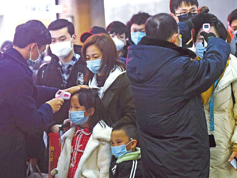 ممرض يفحص حرارة ركاب في محطة قكارات هانغزو الصينية أمس (رويترز)