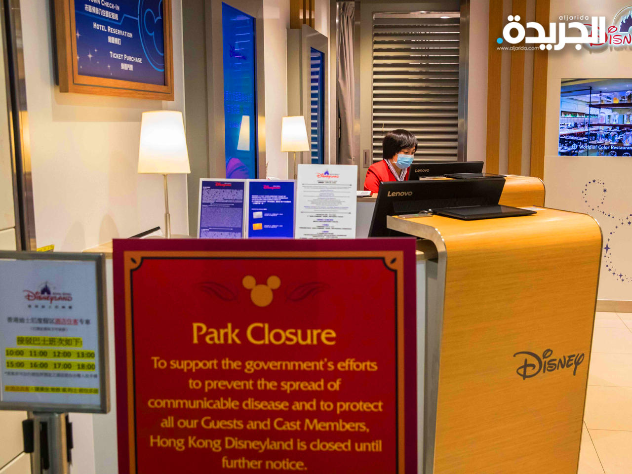 موظفة إستقبال مرتدية القناع وتظهر لافتة تعلن عن غلق مدينة الألعاب