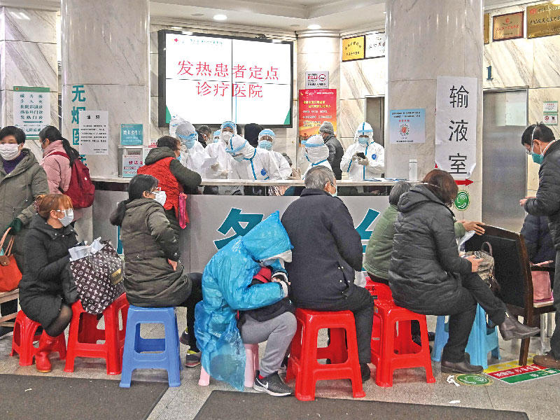 ممرضون يعاينون مجموعة أشخاص في ووهان  (أ ف ب)