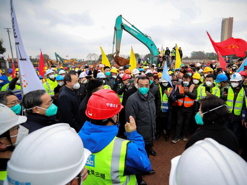 رئيس الوزراء الصيني لي كه تشيانغ وهو يرتدي قناعًا يتحدث مع الموظفين أثناء زيارته لموقع البناء حيث يتم بناء المستشفى الجديد لعلاج مرضى فيروس كورونا