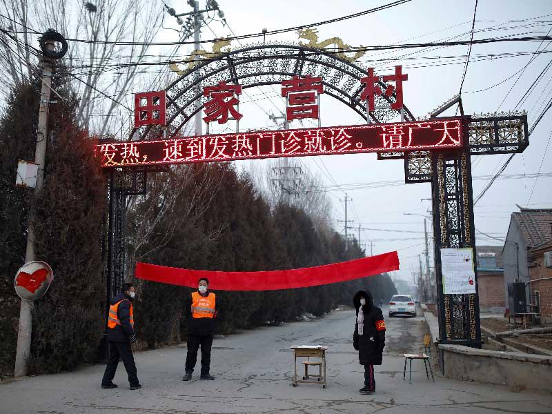 أعضاء لجنة القرية الذين يرتدون أقنعة الوجه والسترات عند مدخل مجتمع لمنع الأجانب من الدخو