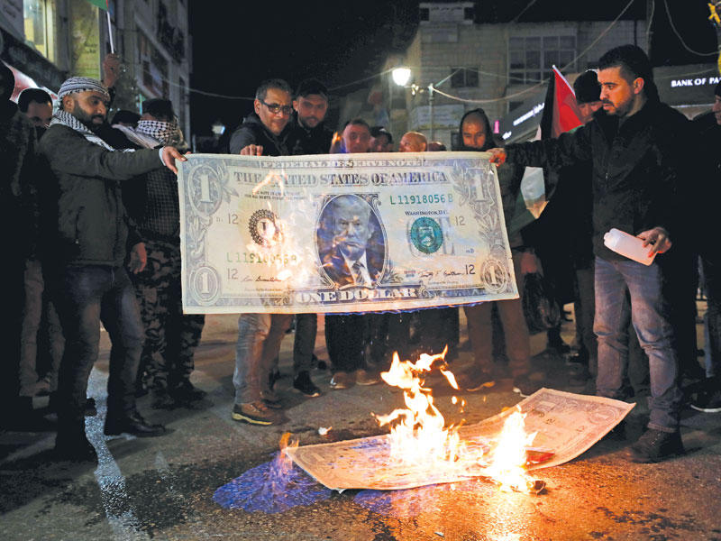 الفلسطينيون يحرقون دولار يحمل صورة الرئيس الامريكي دونالد ترامب احتجاجا علي صفقة القرن