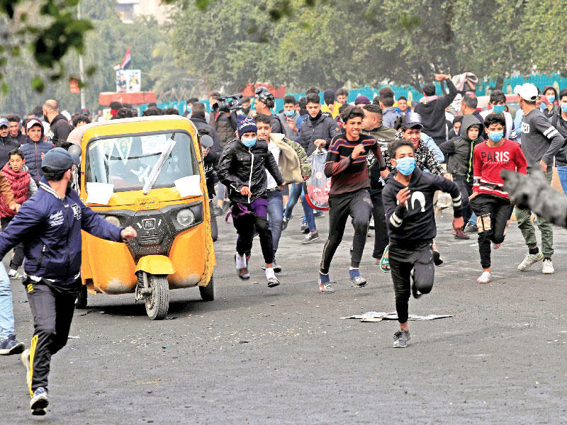 محتجون يفرون خلال مواجهات مع قوات الأمن في بغداد أمس (رويترز)