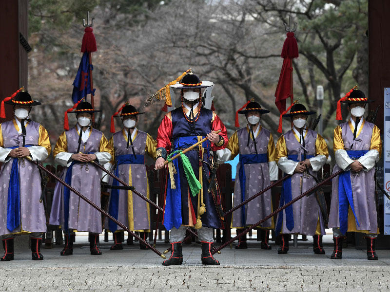 حرس القصر الرئاسي في كوريا الجنوبية يضعون أقنعة خلال تقديمهم عرضهم التقليدي للسياح في سيول أمس (أ ف ب)