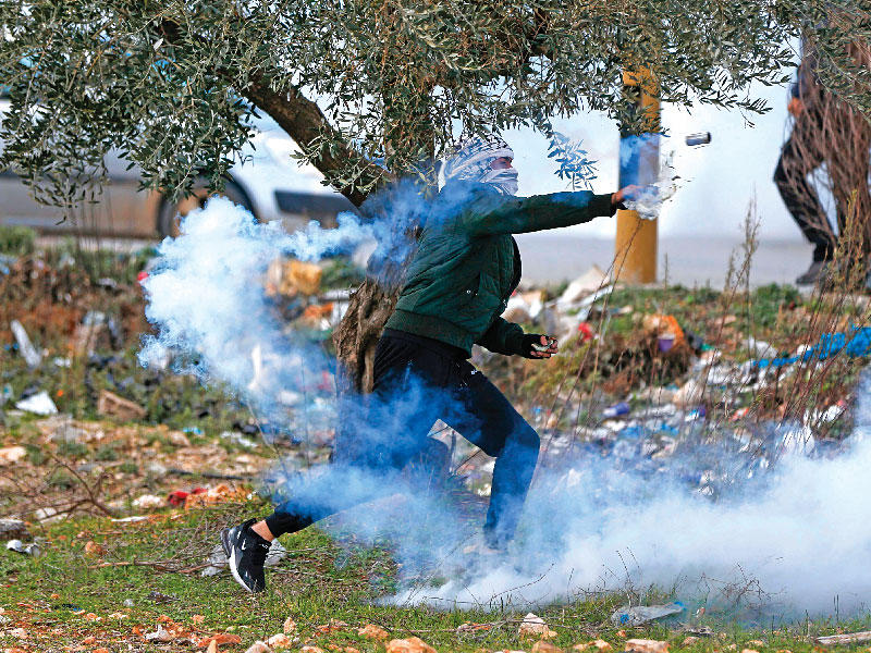 فلسطيني يعيد إلقاء عبوة غاز على القوات الإسرائيلية في رام الله أمس  (أ ف ب)