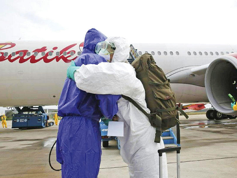 معانقة بين موظفين من السفارة الإندويسية بعد عودتهما من الصين أمس     (أ ف ب)