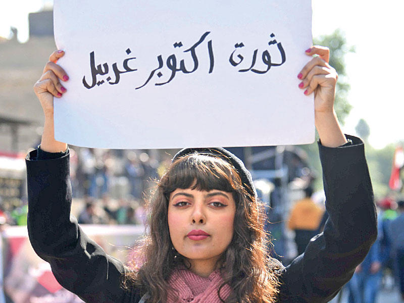 طالبة عراقية ترفع لافتة ببغداد كتب عليها «ثورة أكتوبر غربيل» (منخل) (أي بي ايه)n