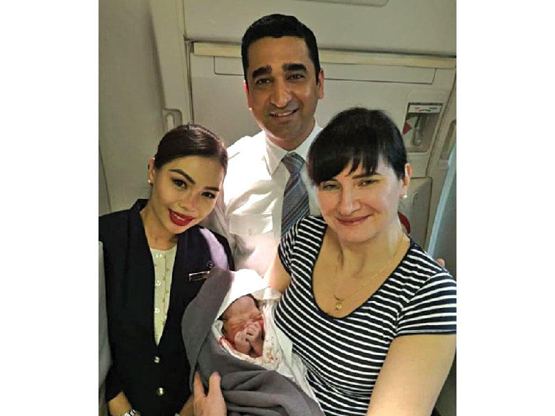 الطبيبة الأوكرانية تحمل الطفل المولود علي متن طائرة الخطوط الجوية القطرية