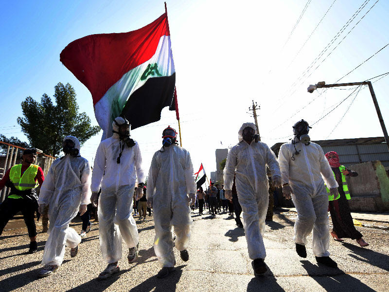 عراقيون يرتدون أقنعة واقية خلال تظاهرة في بغداد أمس ( أ ف ب) 