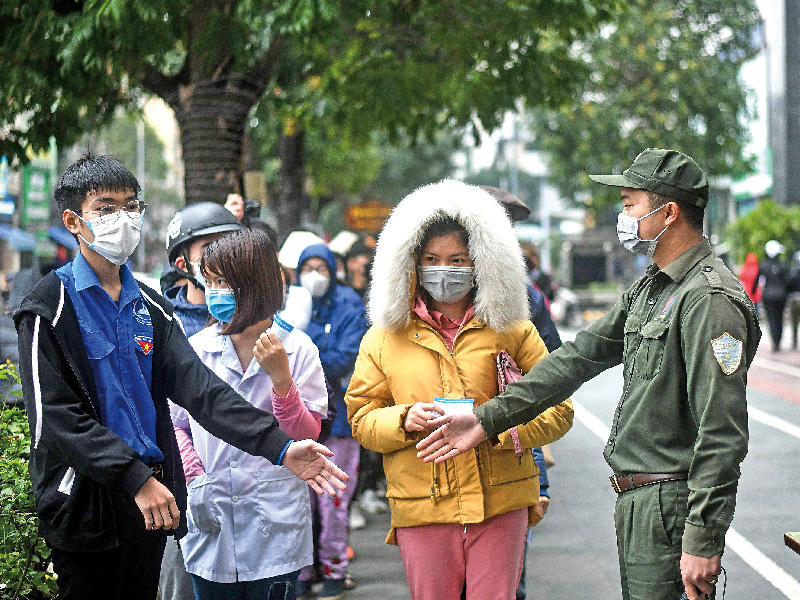 فيتناميون ينتظرون دورهم للحصول على كمامات مجانية في العاصمة هانوي أمس (أ ف ب)