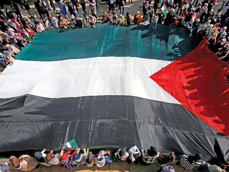 مغاربة يحملون علماً فلسطينياً خلال تظاهرة ضد صفقة القرن في الرباط أمس (رويترز)