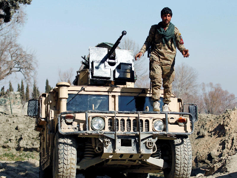 أحد أفراد قوات الأمن الأفغانية في حراسة بالقرب من جانب حادثة قتل فيها جنديان أمريكيان