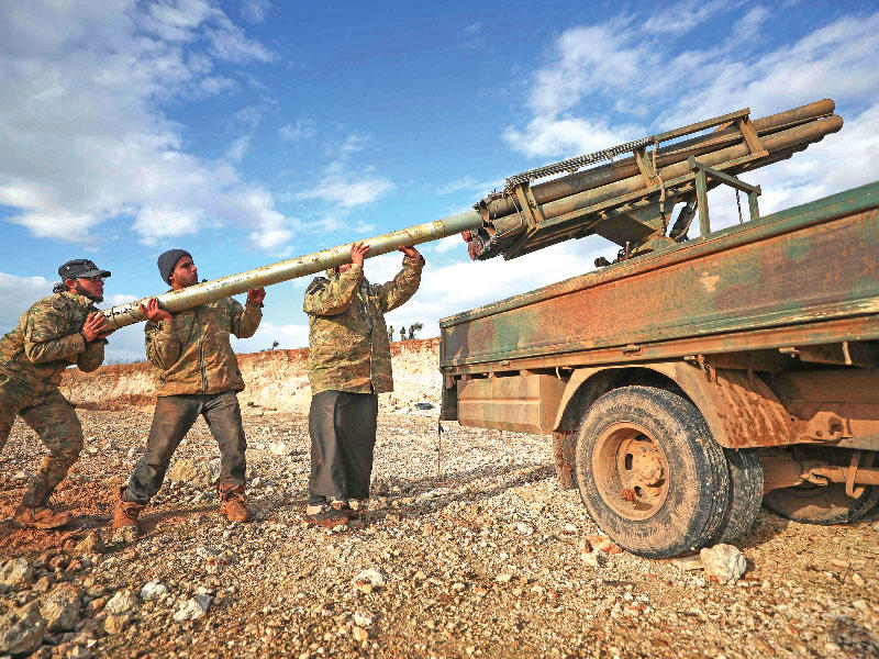 مقاتلون سوريون يجهزون قاذفة صواريخ غراد في إدلب أمس الأول (أ ف ب)