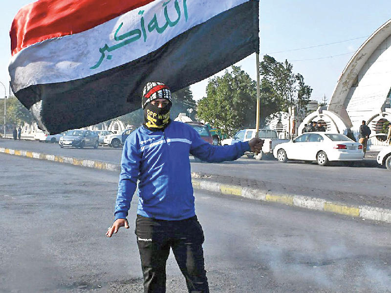 عراقي يرفع علماً خلال قطع طريق بالناصرية أمس    (أ ف ب) 
