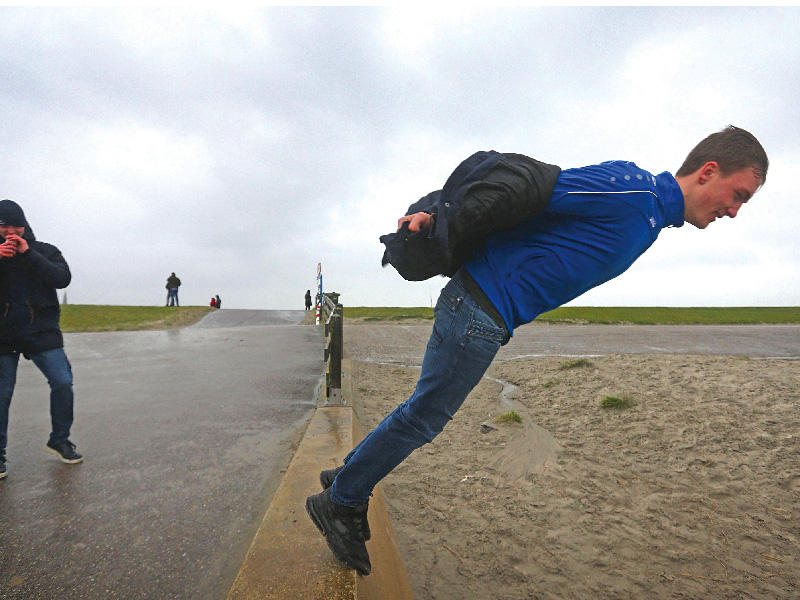 رجل يقف على حافة جدار بحري أثناء العاصفة سيارا في هارلينجن في 9 فبراير الجاري، والتي جلبت رياحاً شديدة غير عادية في جميع أنحاء أوروبا وأدت إلى إلغاء الأحداث الرياضية الوطنية والدولية. (أ ف ب)n