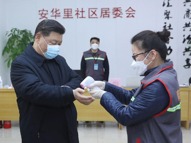 الرئيس الصيني شي جينبينغ، وهو يرتدي قناعًا واقيًا أثناء قيام مسؤول صحي بالتحقق من درجة حرارة جسده